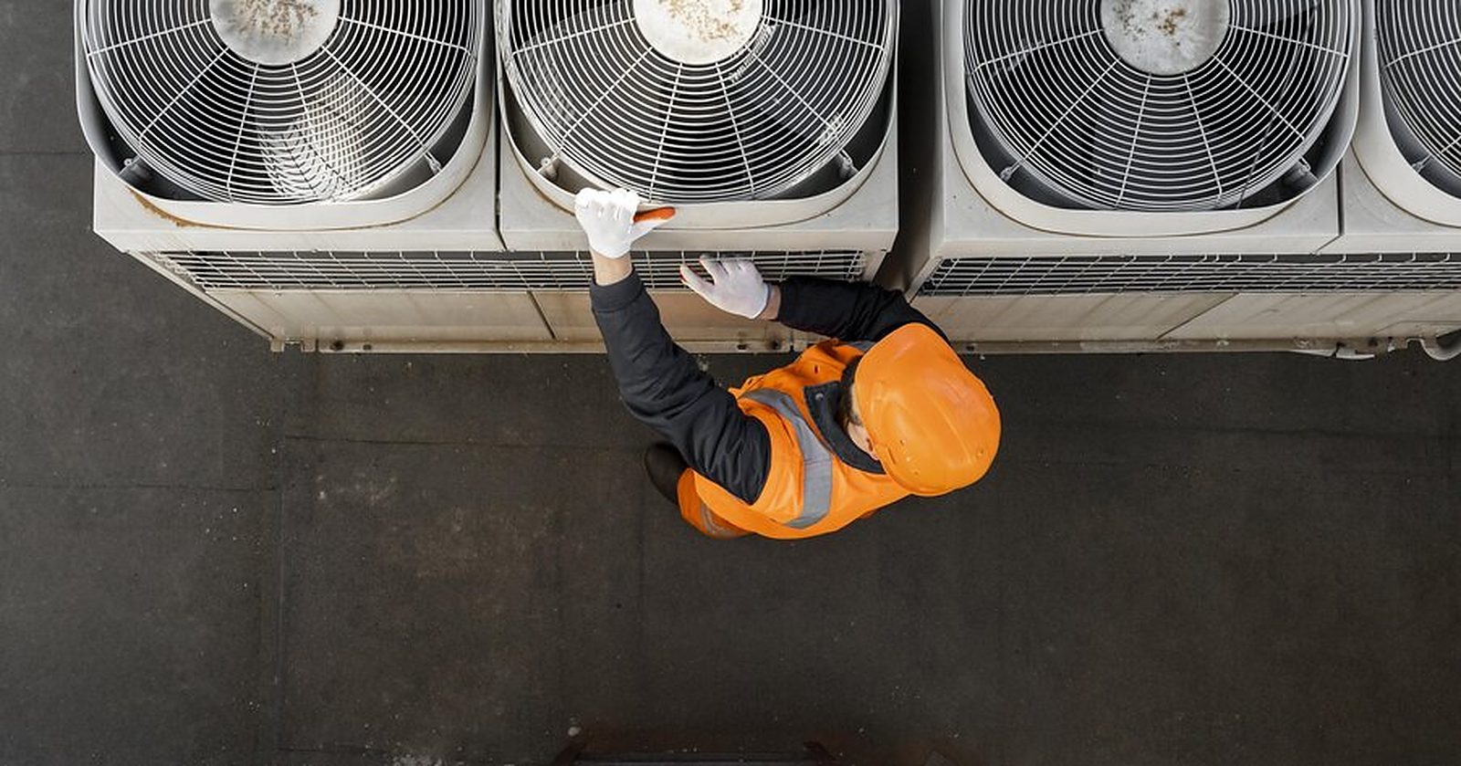 Monteur bij buitenunits van warmtepompen (sfeerbeeld)